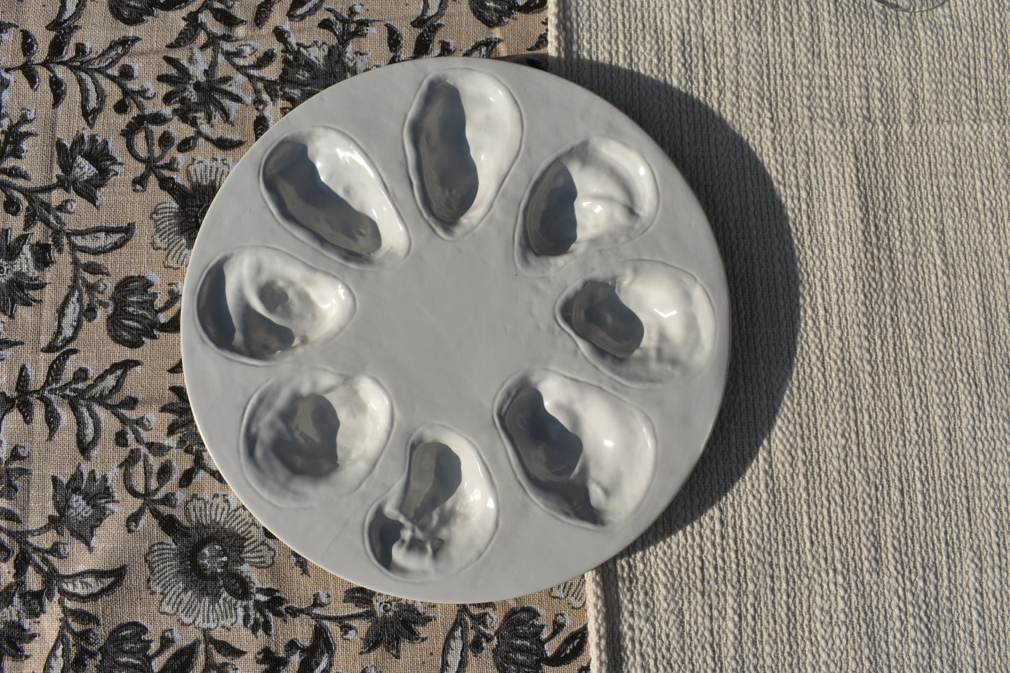 Een ronde witte oesterschaal met ruimte voor 8 oesters