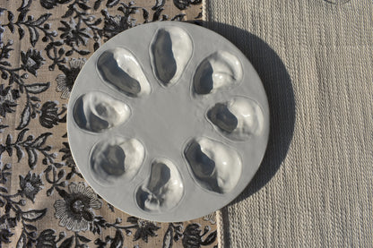 Een ronde witte oesterschaal met ruimte voor 8 oesters